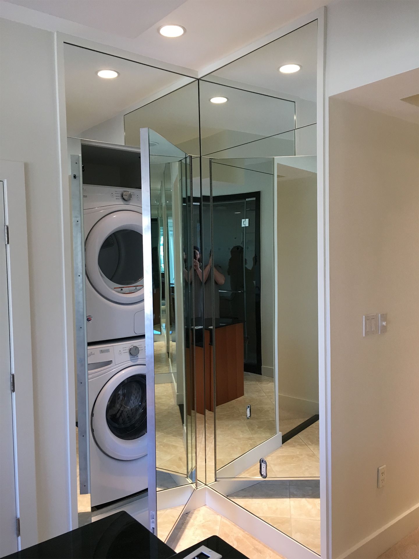 A washer and dryer are stacked on top of each other in a mirrored room.