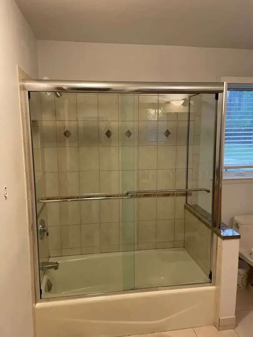 A bathroom with a bathtub and a glass shower door.