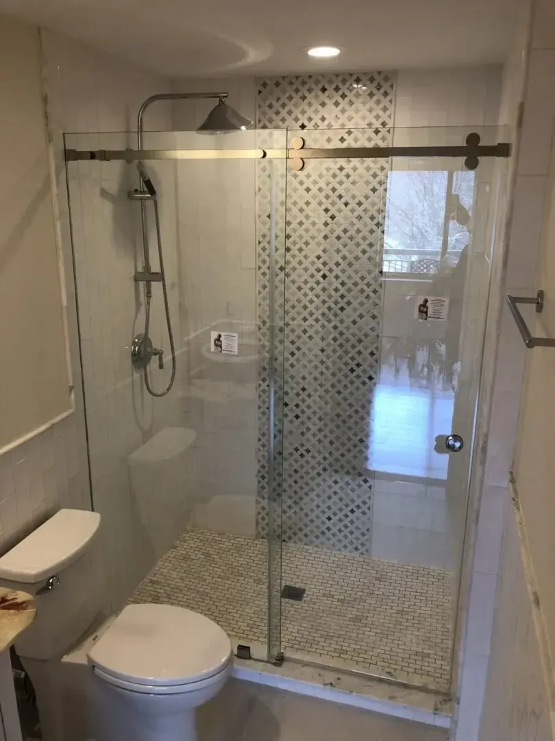 A bathroom with a toilet , sink and shower stall.
