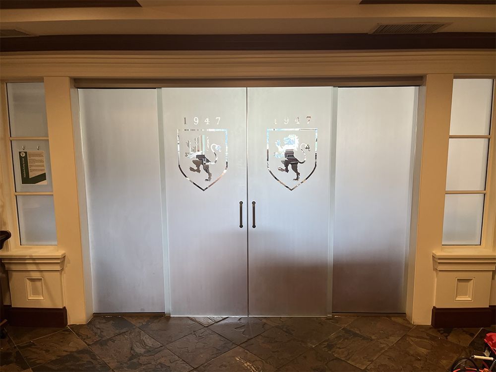 A pair of sliding glass doors with a coat of arms on them.