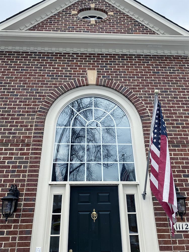 A brick building with a black door and an american flag in front of it.