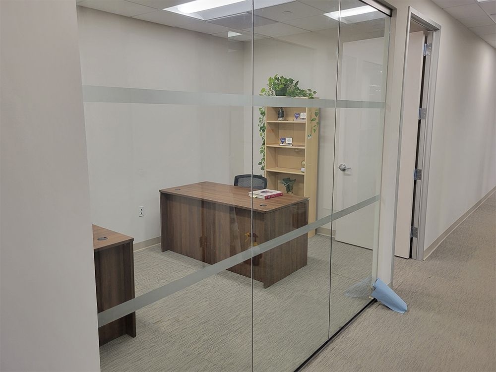 A room with a desk and chair in it and a glass wall.