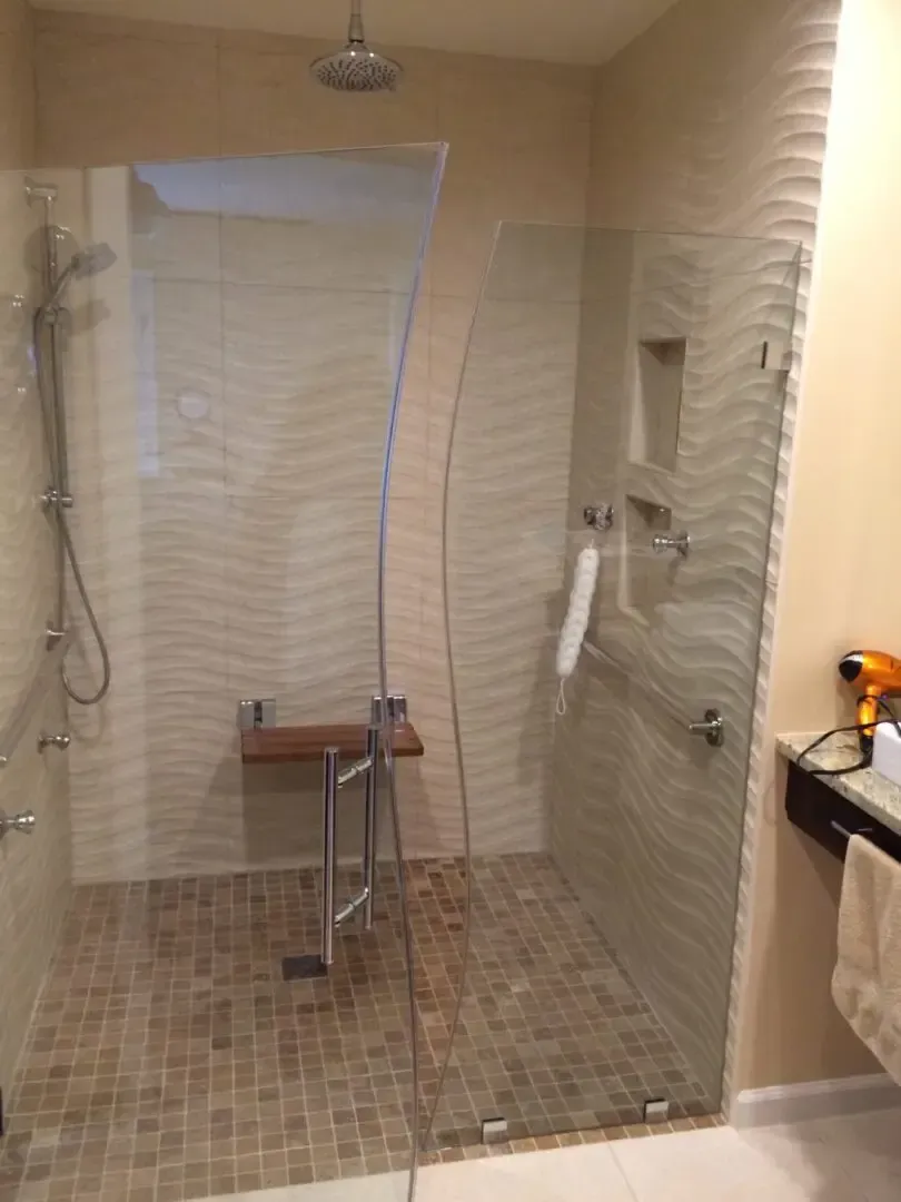A bathroom with a walk in shower with a glass door.