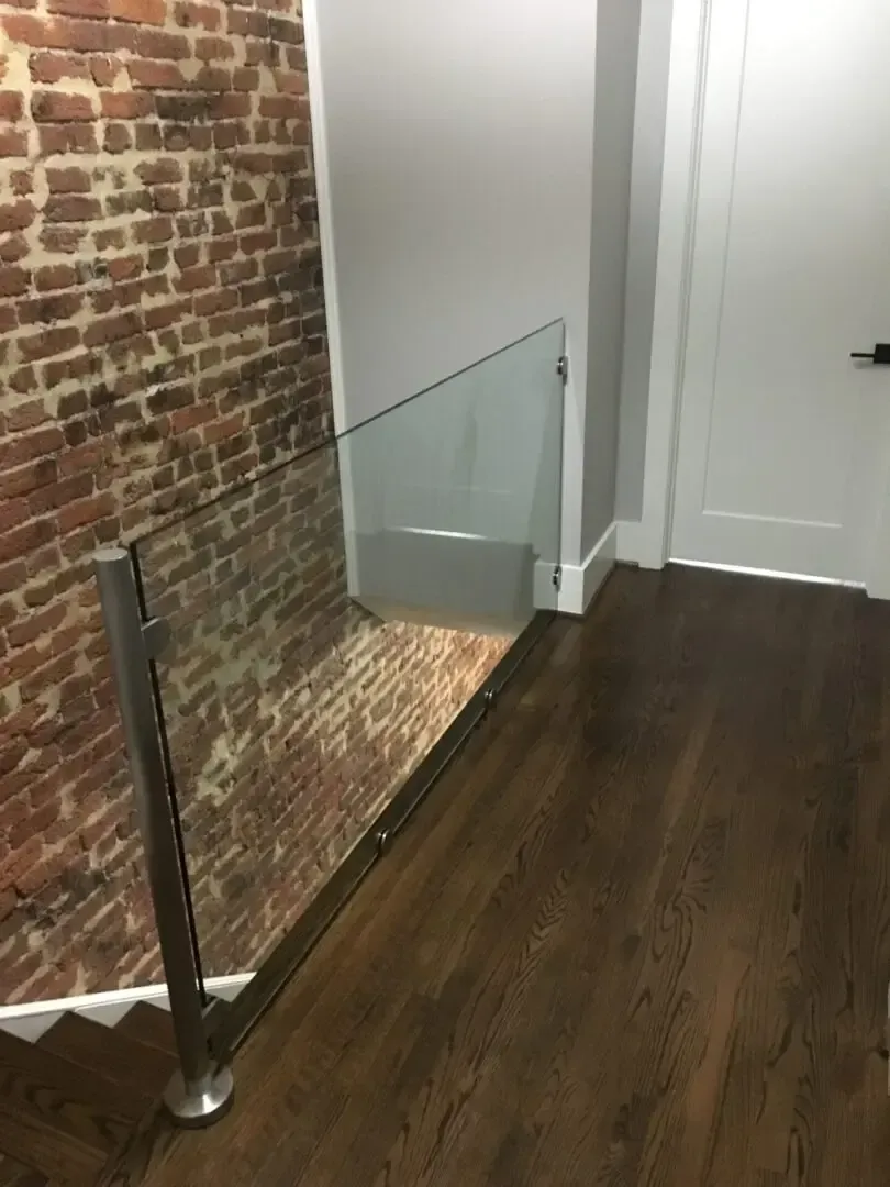 A staircase with a glass railing and a brick wall.