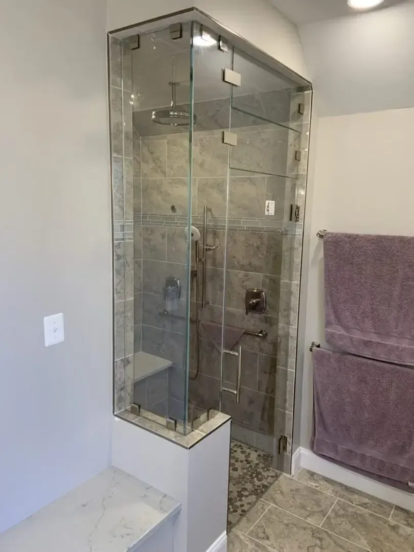 A bathroom with a glass shower door and purple towels.