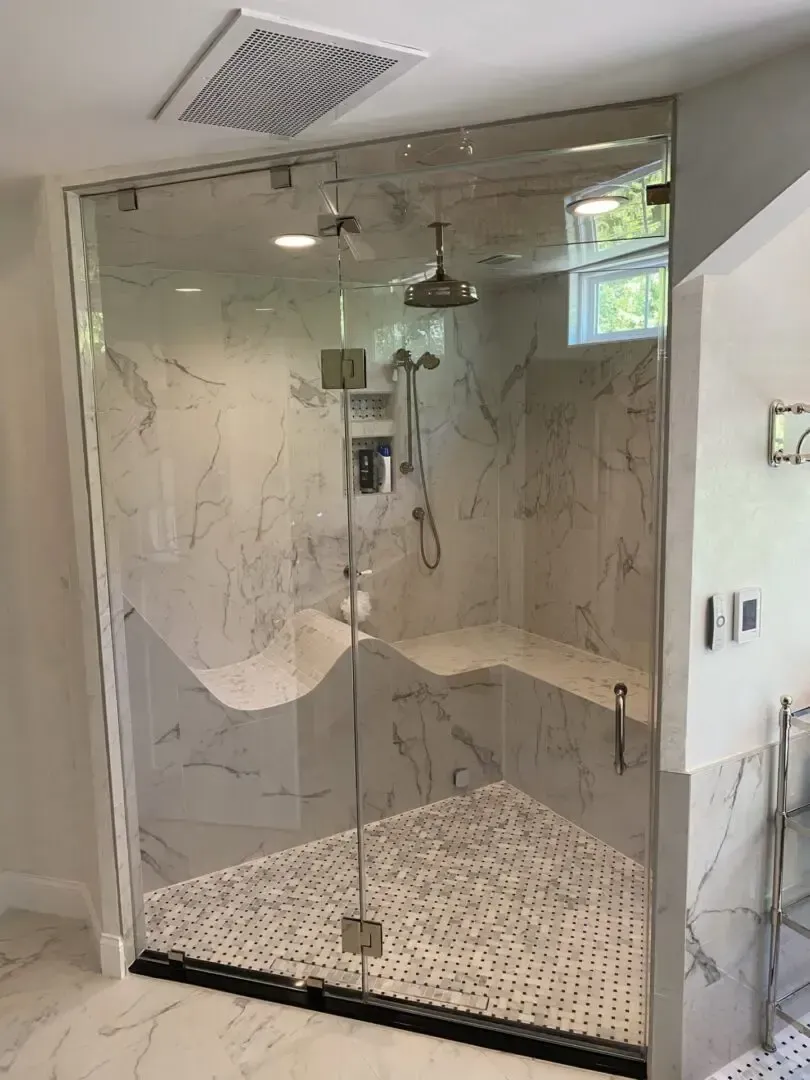 A bathroom with a walk in shower with a glass door.
