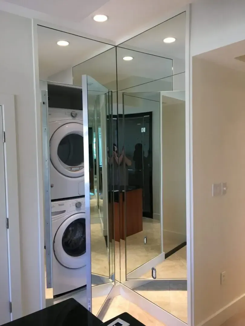 A washer and dryer are stacked on top of each other in a mirrored room.