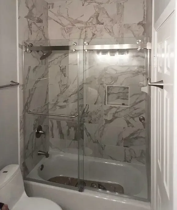A bathroom with a tub , toilet , shower and marble walls.