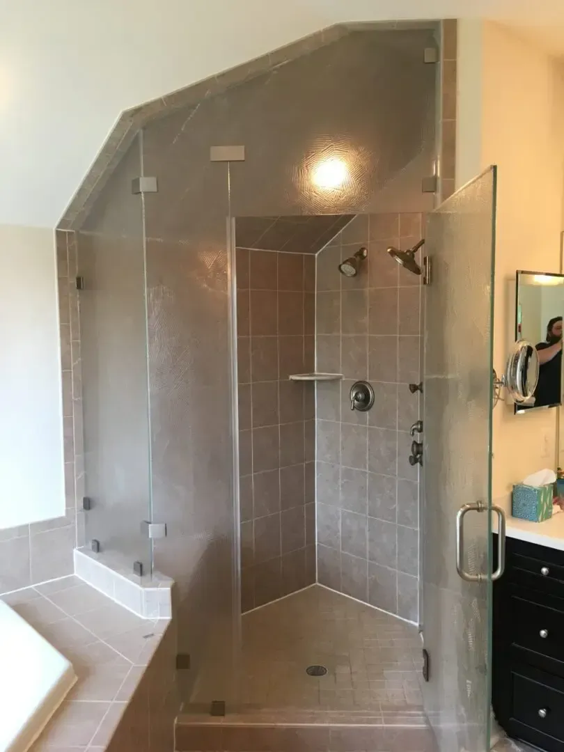 A bathroom with a walk in shower with a glass door.