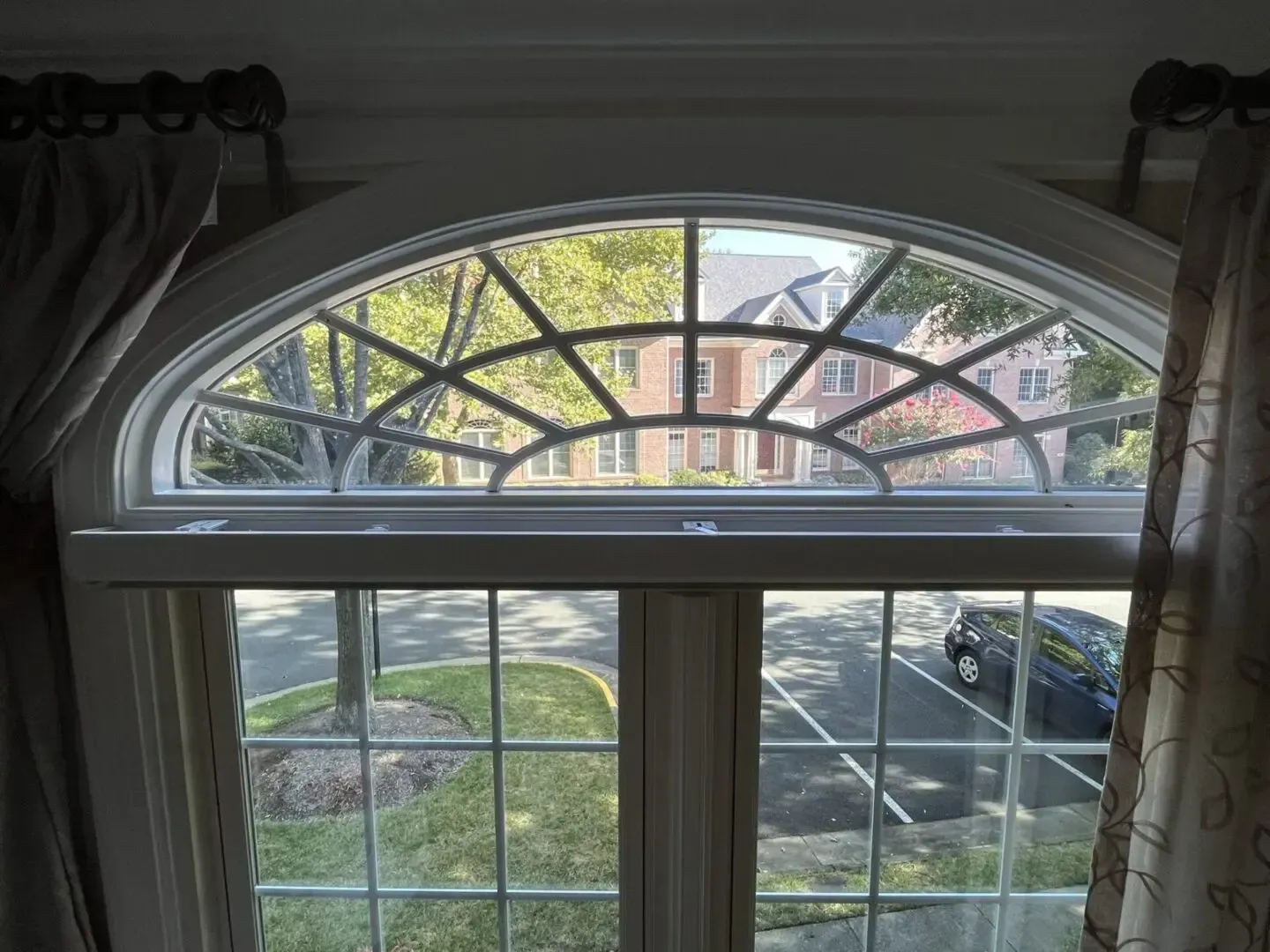 A large arched window with a view of a residential area.