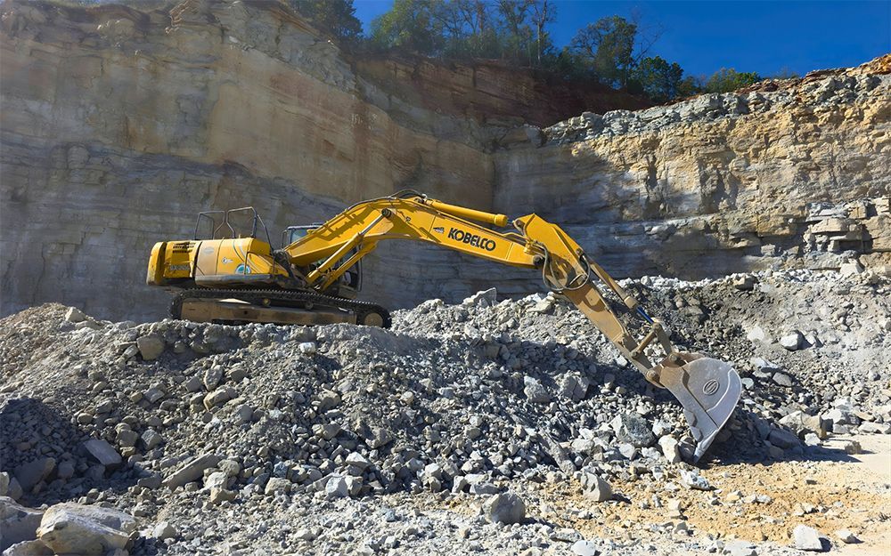 Yellow excavator in a quarry, moving rocks.