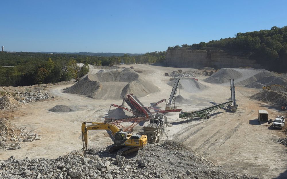 Excavators and machinery at a quarry, processing stone.