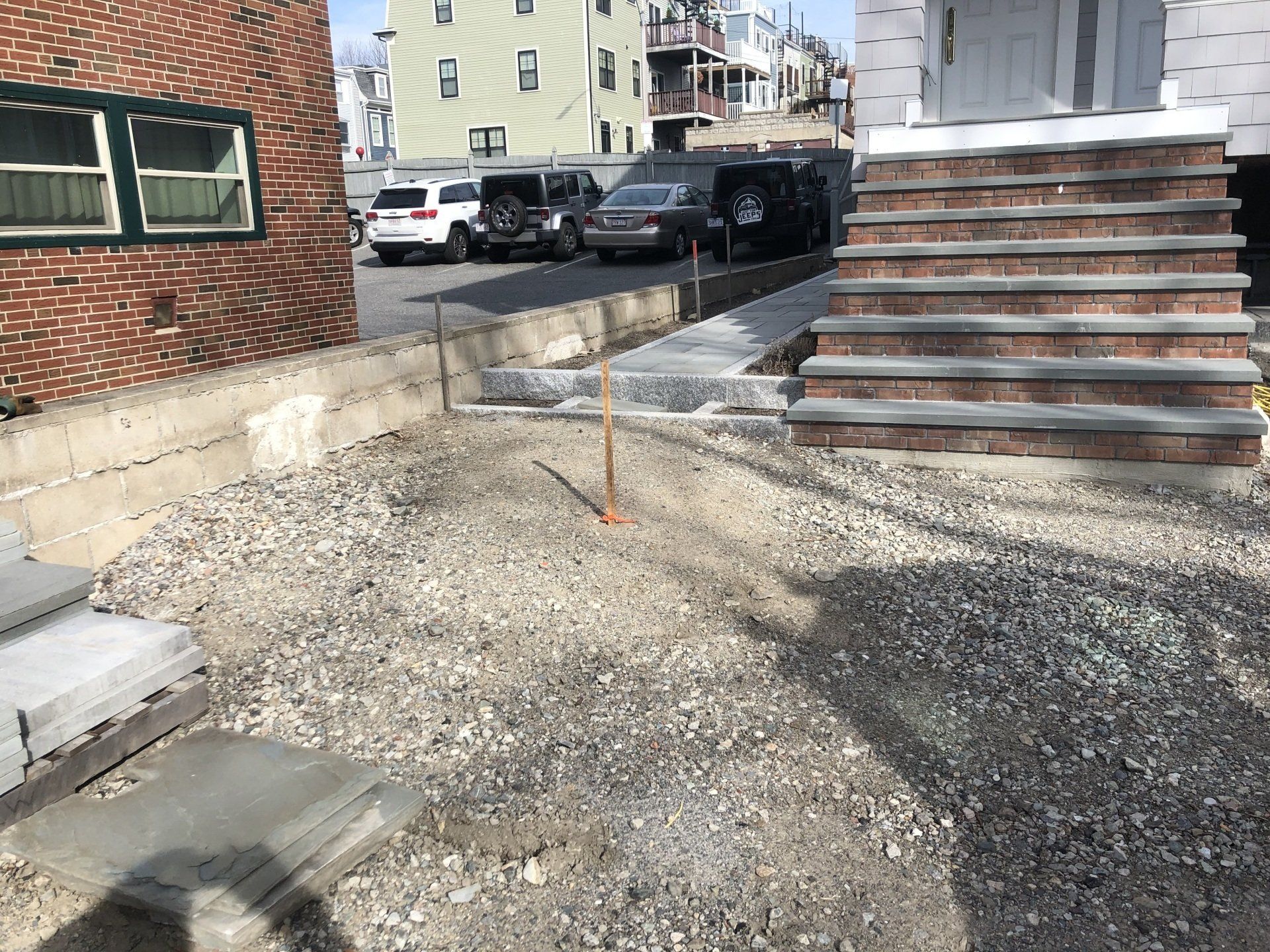 A brick building with stairs and cars parked in front of it.