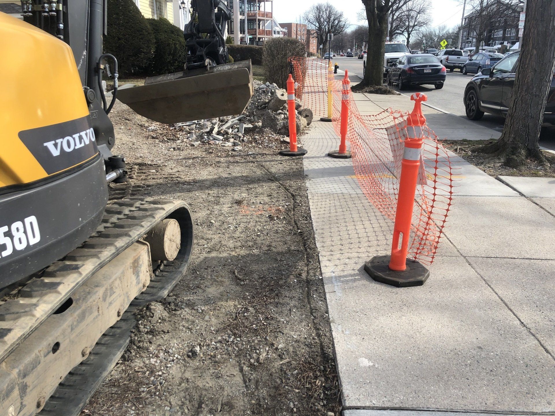 A yellow and black volvo excavator is parked on the sidewalk