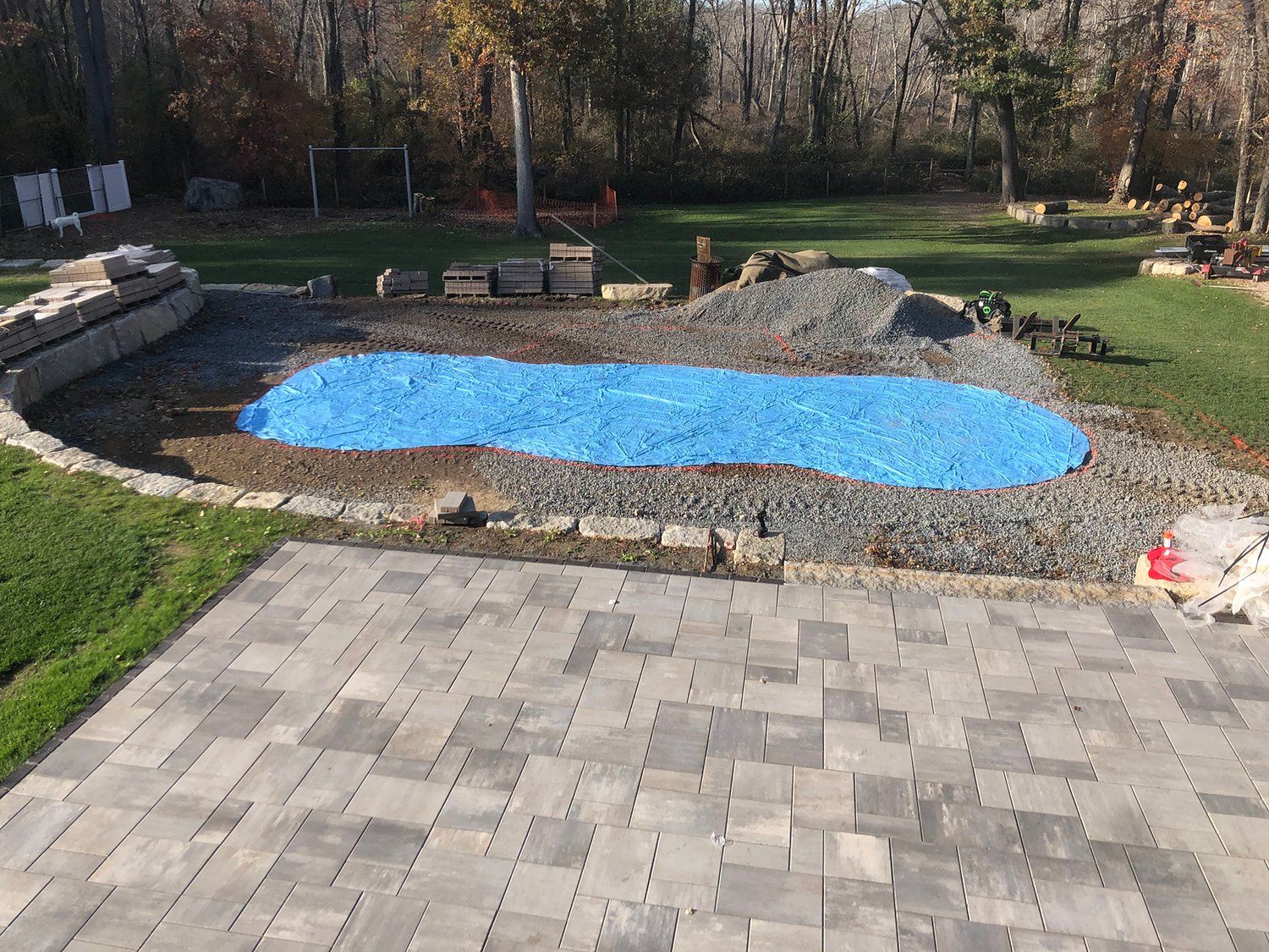 A blue tarp is covering a large pool in a backyard.