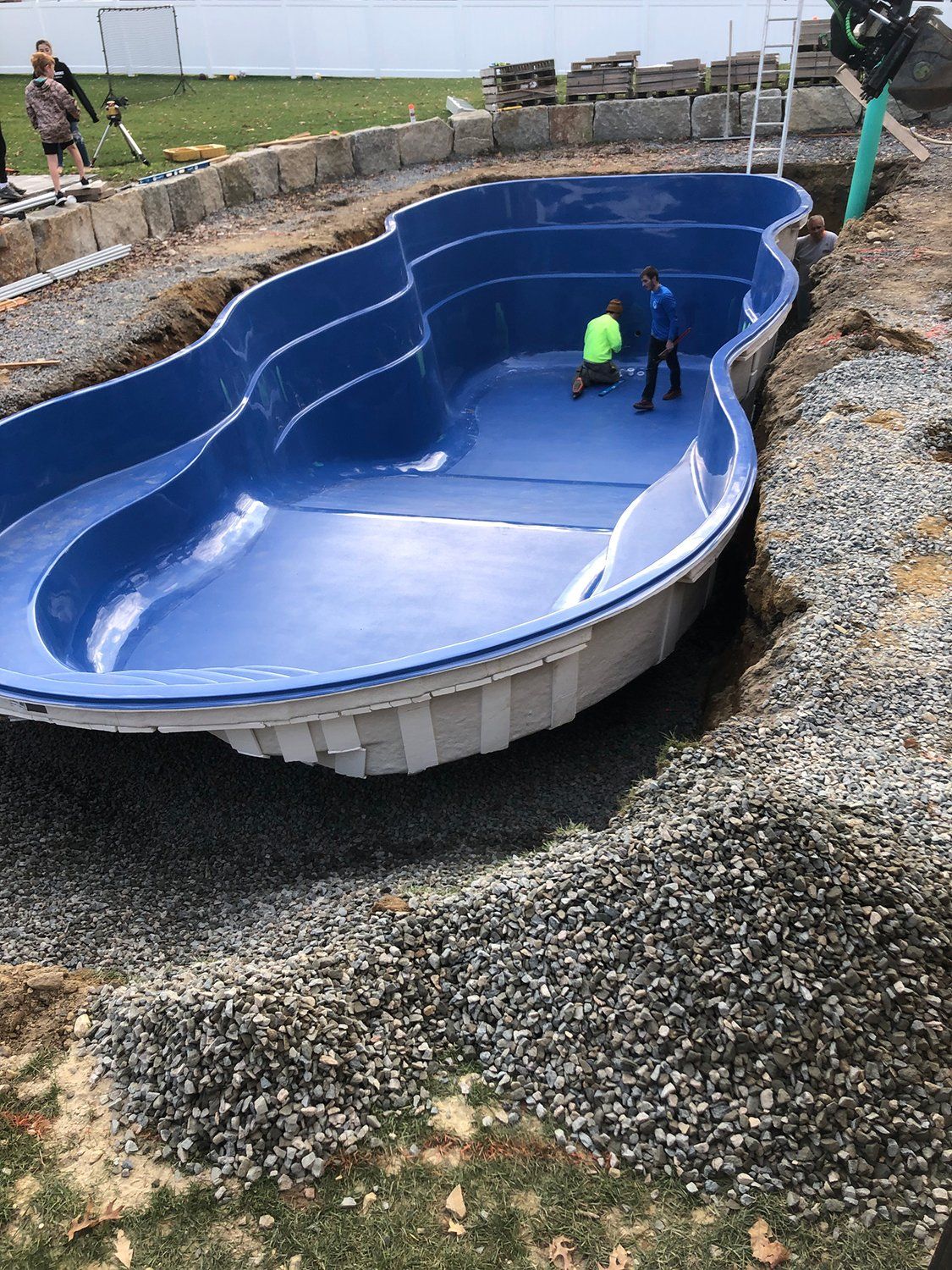 A large blue swimming pool is being built in a backyard.