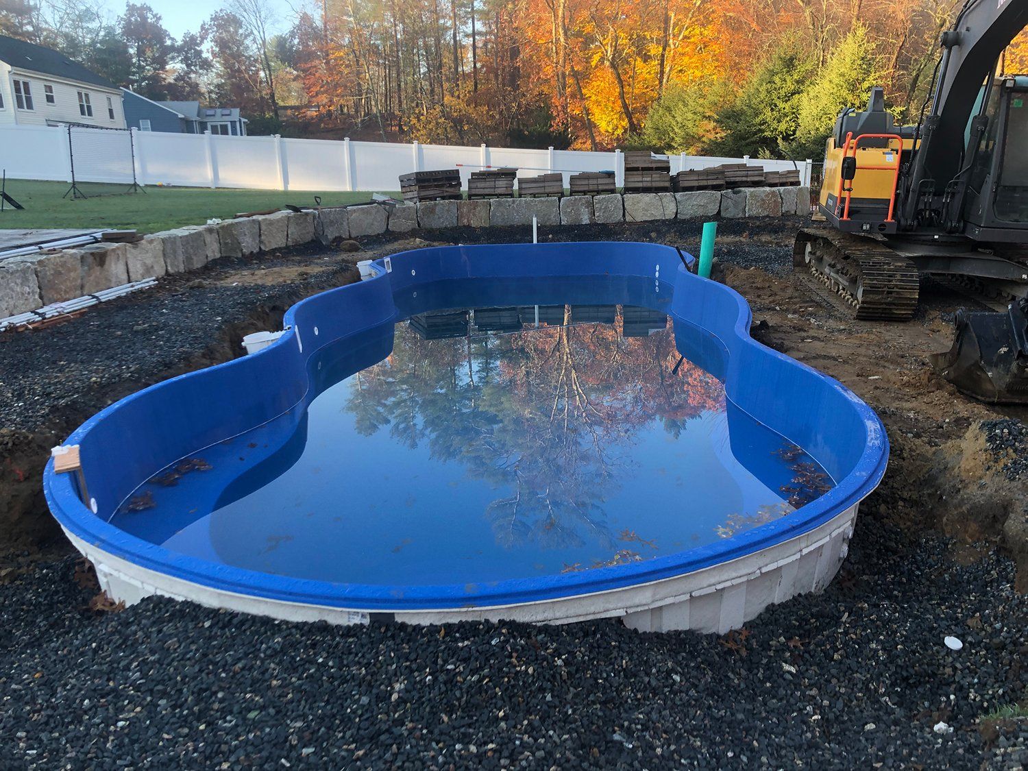 A large blue swimming pool is being built in a backyard.