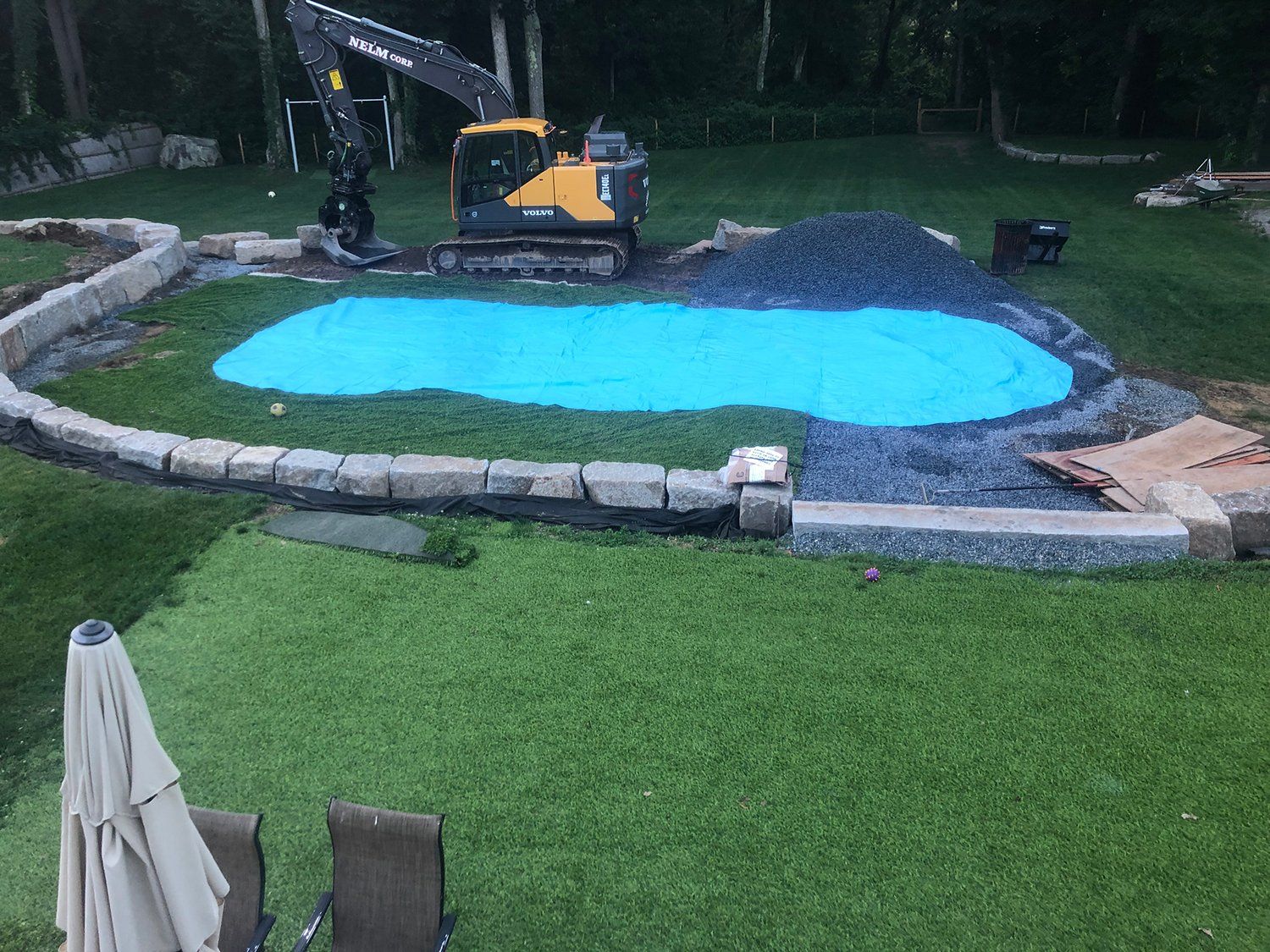 A large blue tarp is covering a swimming pool in a backyard.