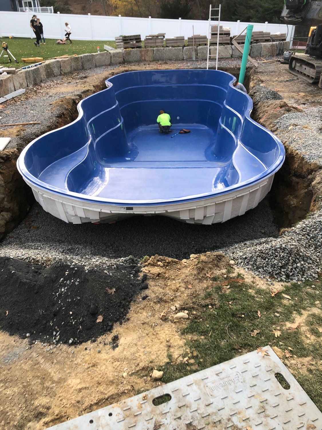 A large blue swimming pool is being built in a backyard.