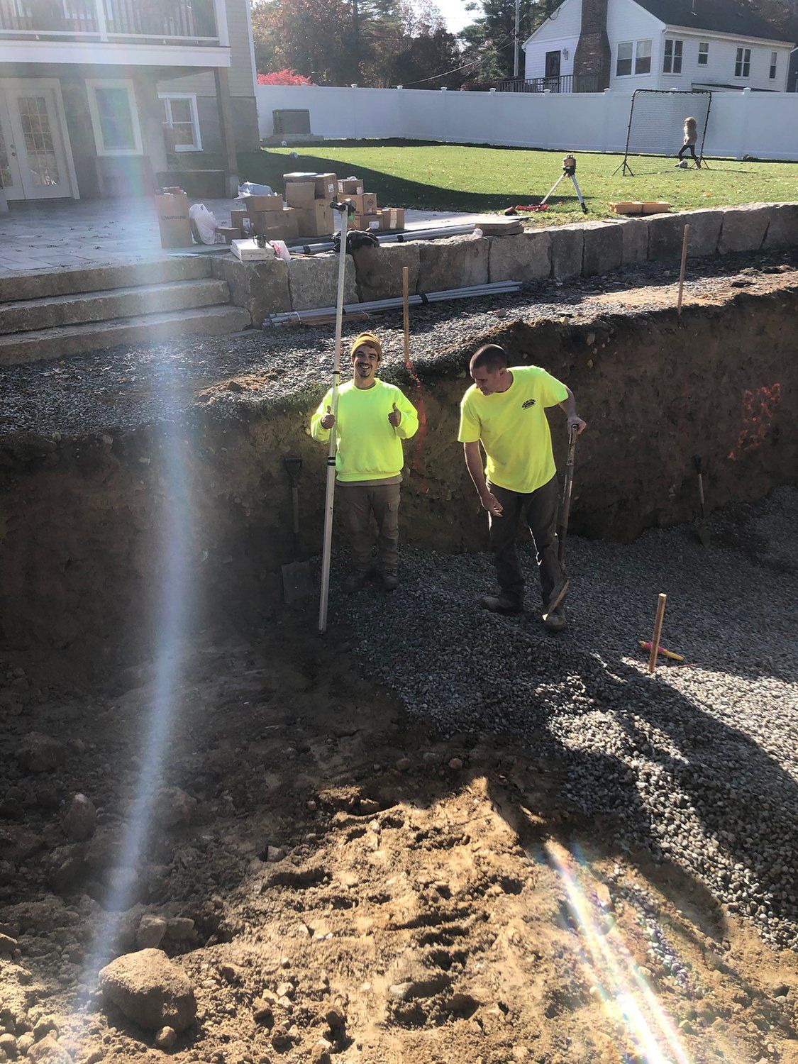 Two construction workers are standing in a pile of dirt.