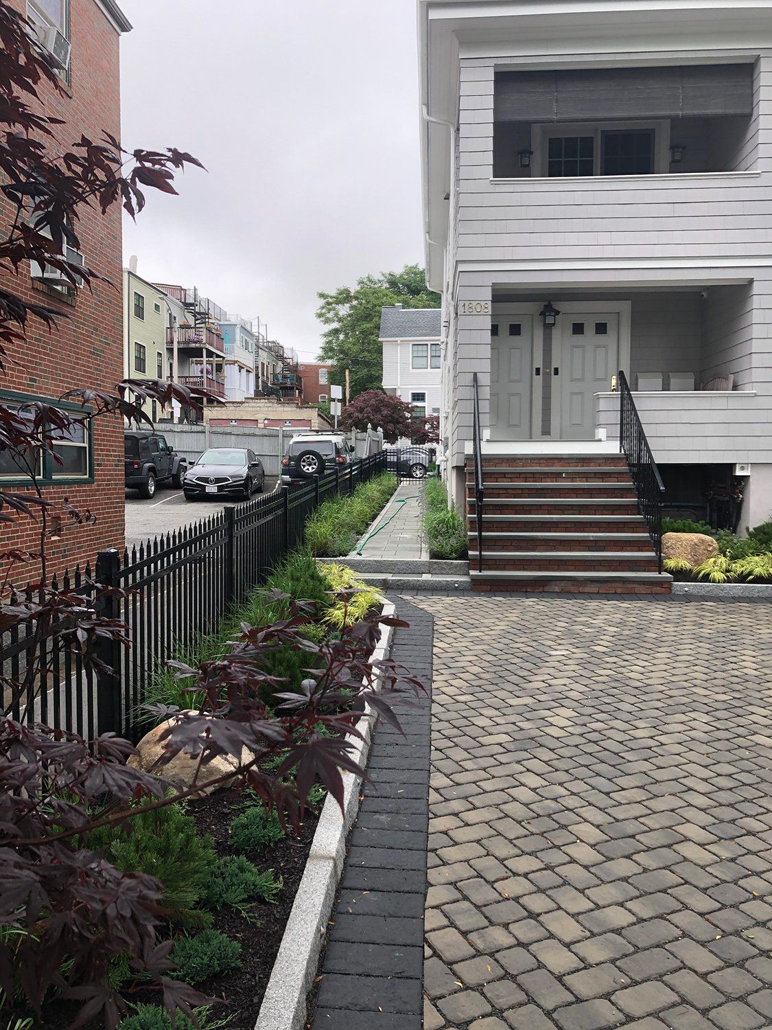 A brick walkway leading to a house with stairs leading up to the front door.