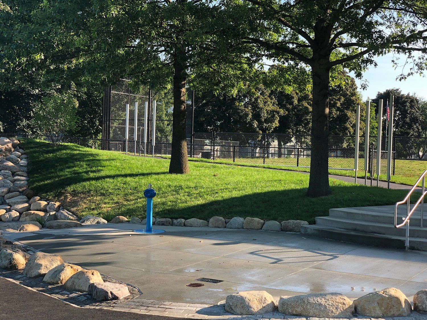 A blue fire hydrant is in the middle of a park.