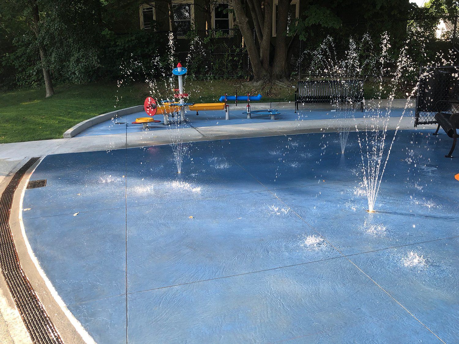 A fountain in a park with a train in the background