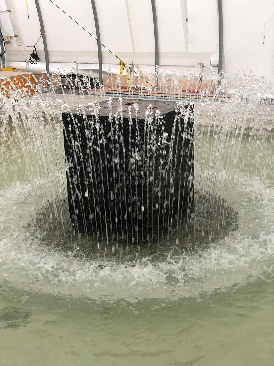 A fountain is being built in a greenhouse and water is coming out of it.