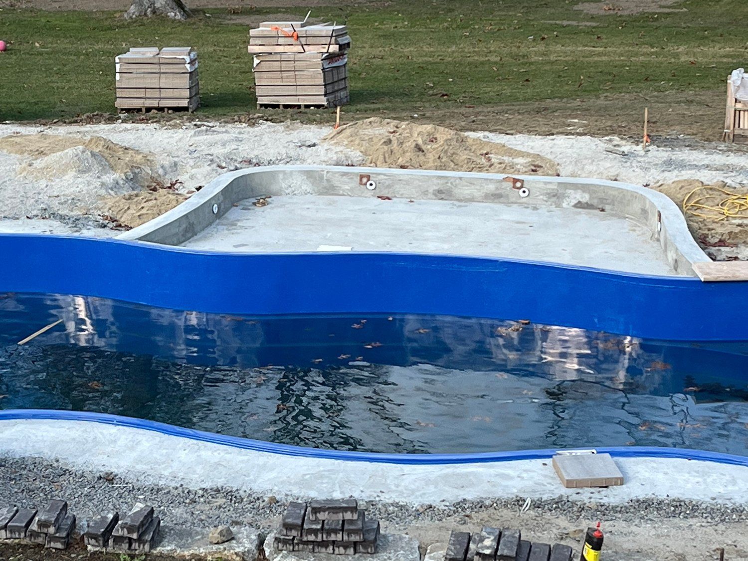 A large swimming pool is being built in a field.