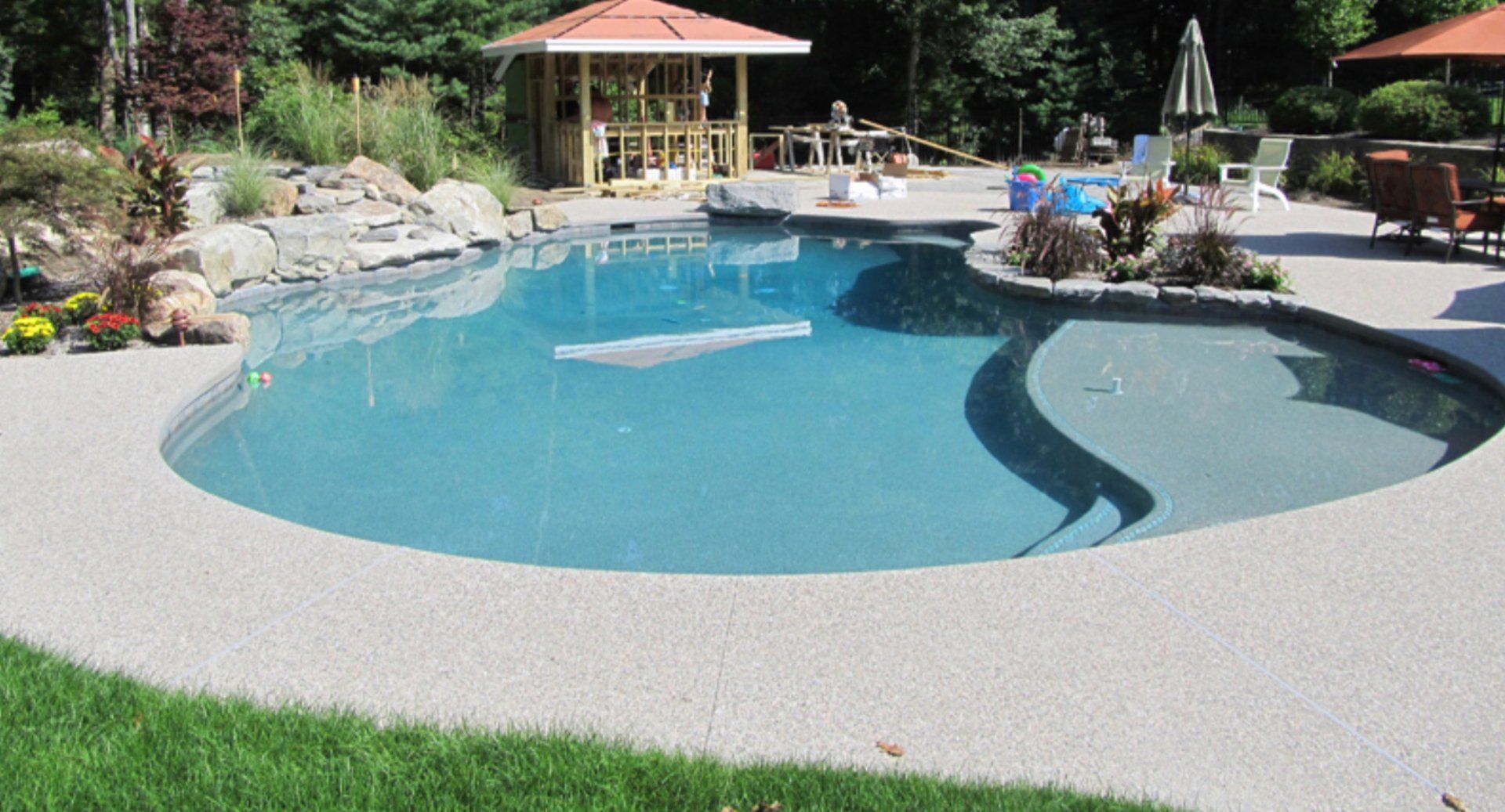 A large swimming pool with a gazebo in the background