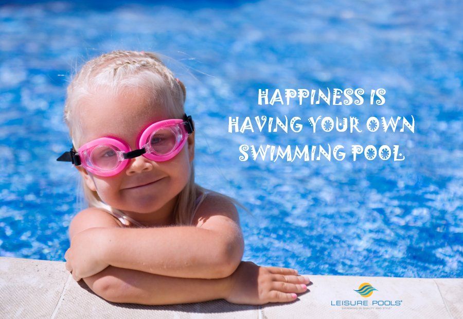 A little girl wearing goggles is sitting on the edge of a swimming pool.