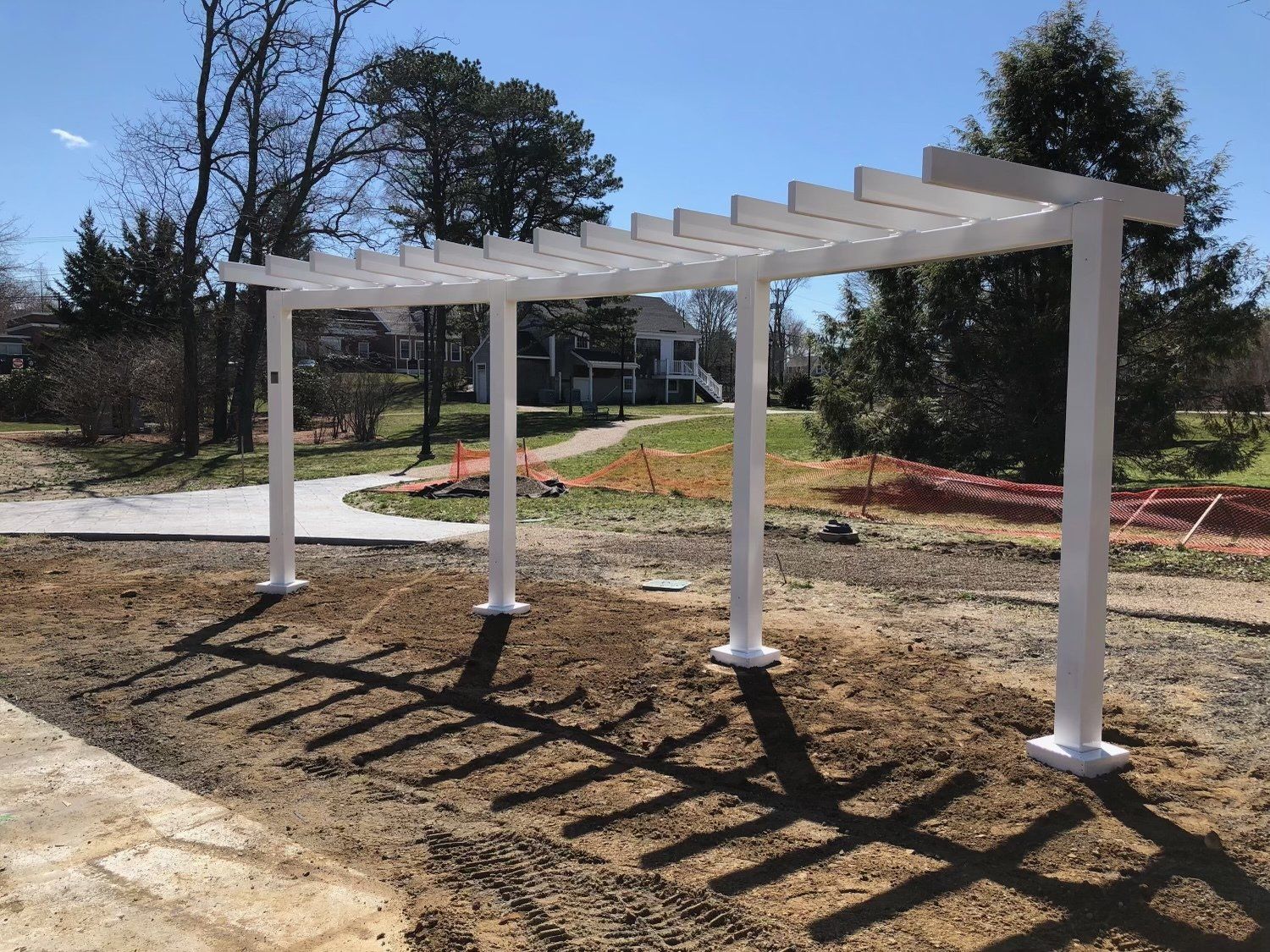 A white pergola is sitting in the middle of a dirt field