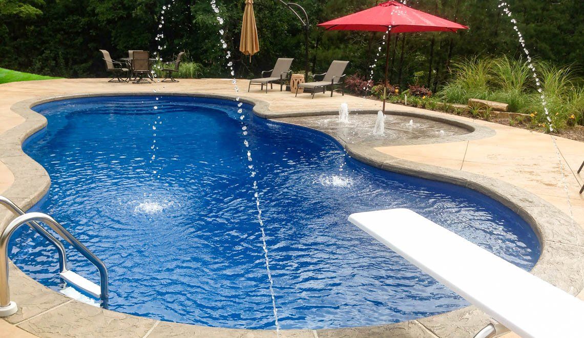 A large swimming pool with a diving board and umbrellas