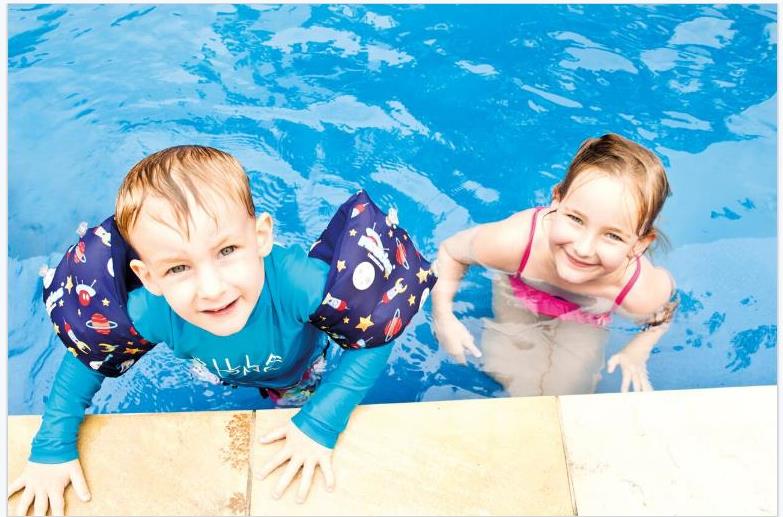 A boy and a girl are swimming in a pool.