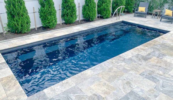 A large swimming pool is sitting on top of a tiled patio.