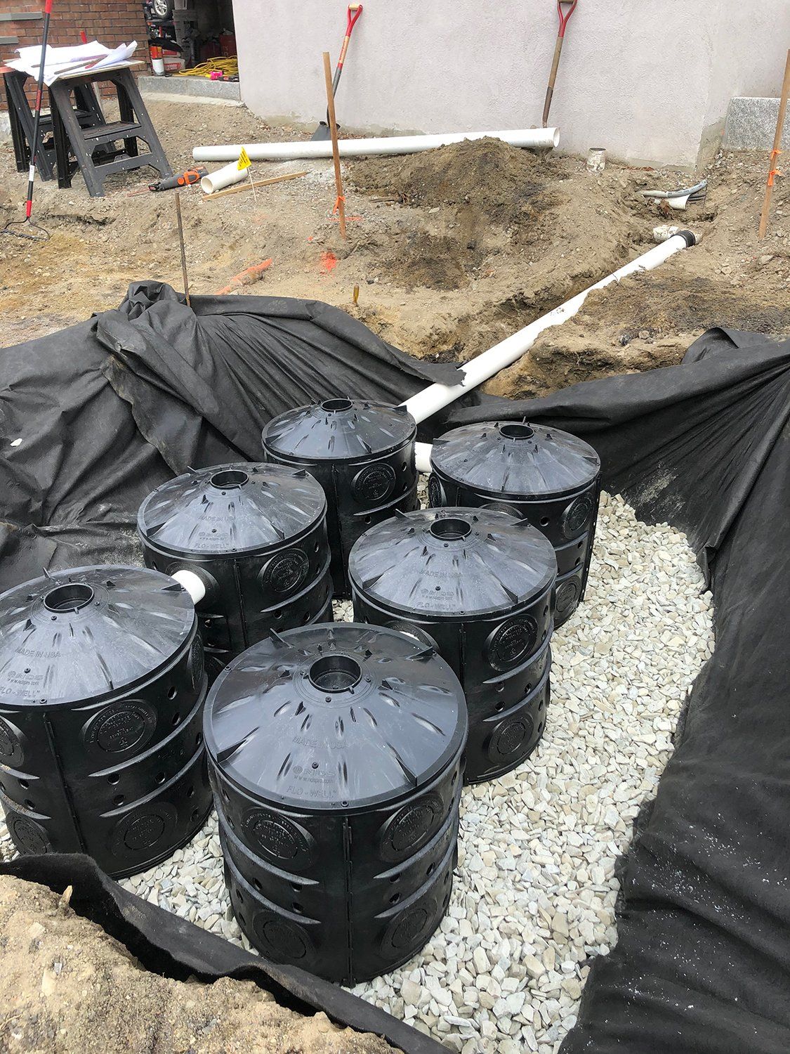 A group of black barrels are sitting on top of a pile of gravel.