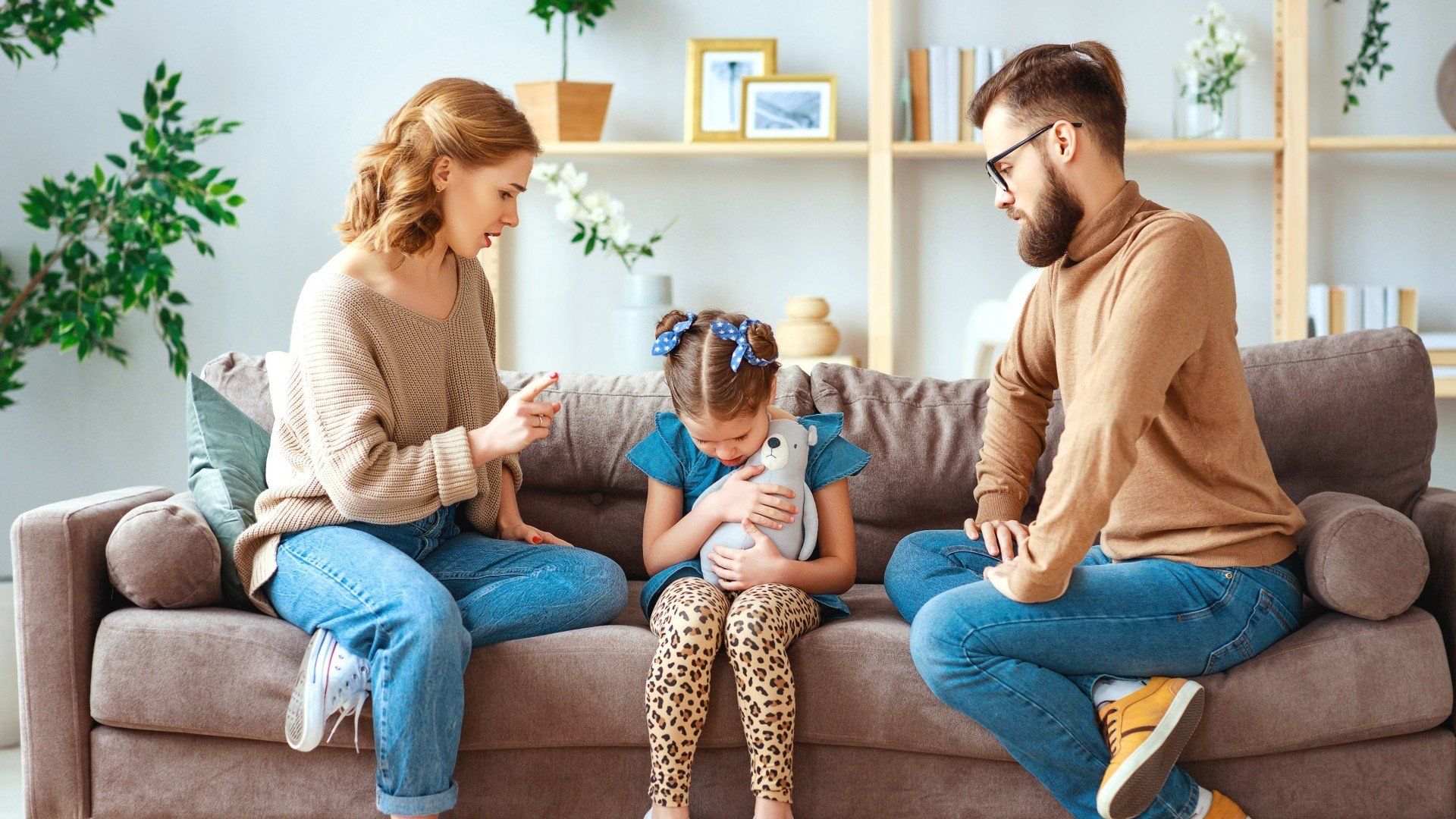 sad child sitting between mother and father on a couch pending divorce and custody hearing