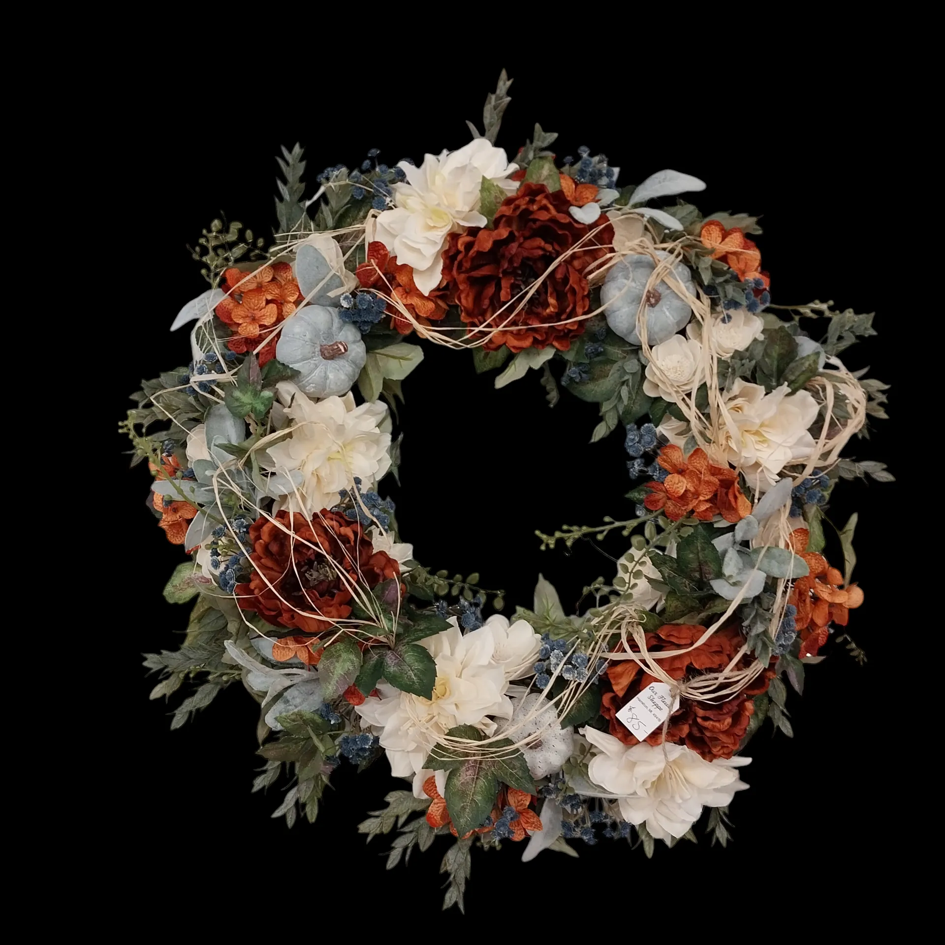 Fall wreath with white, orange, and red flowers, blue pumpkins, and greenery on a black background.