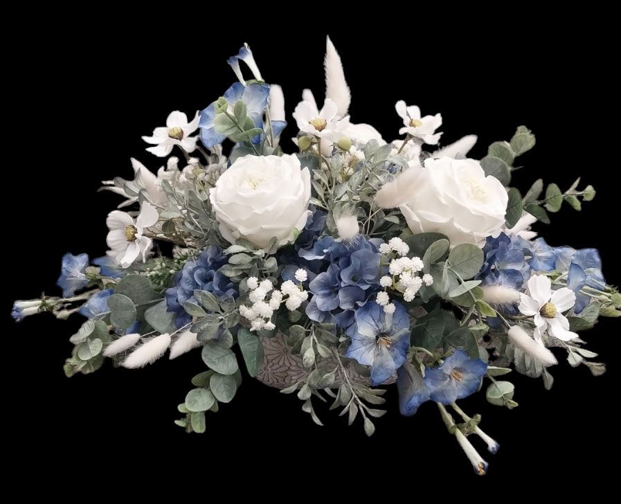 Floral arrangement of white and blue flowers with green foliage against a black background.