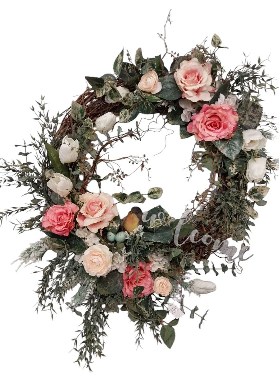 Wreath with pink and white roses, greenery, and small birds nestled in a circular arrangement.