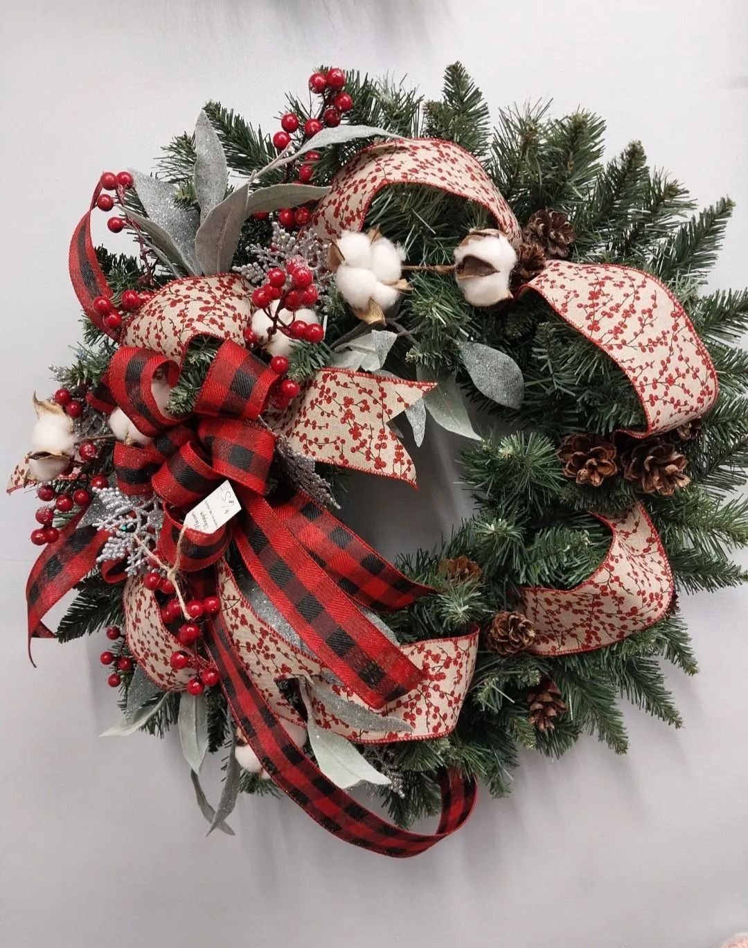 Christmas wreath with red and black buffalo plaid ribbon and cotton accents.