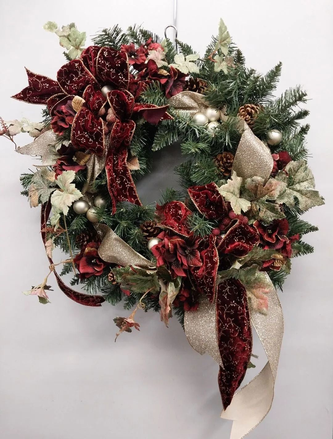 Christmas wreath with red velvet bows and gold accents.