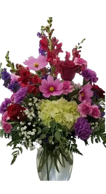Colorful flower arrangement in a clear vase with red, pink, purple, and green blooms.