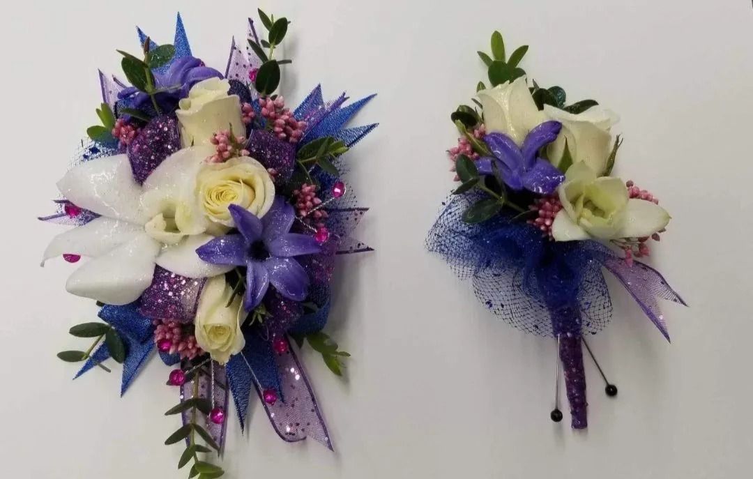 Two corsages: one large, one small, featuring white roses, purple accents, and green foliage on a white background.