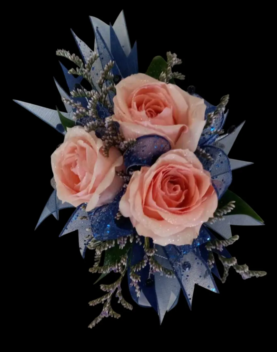 Three peach roses with blue ribbon and silver accents on a black background.
