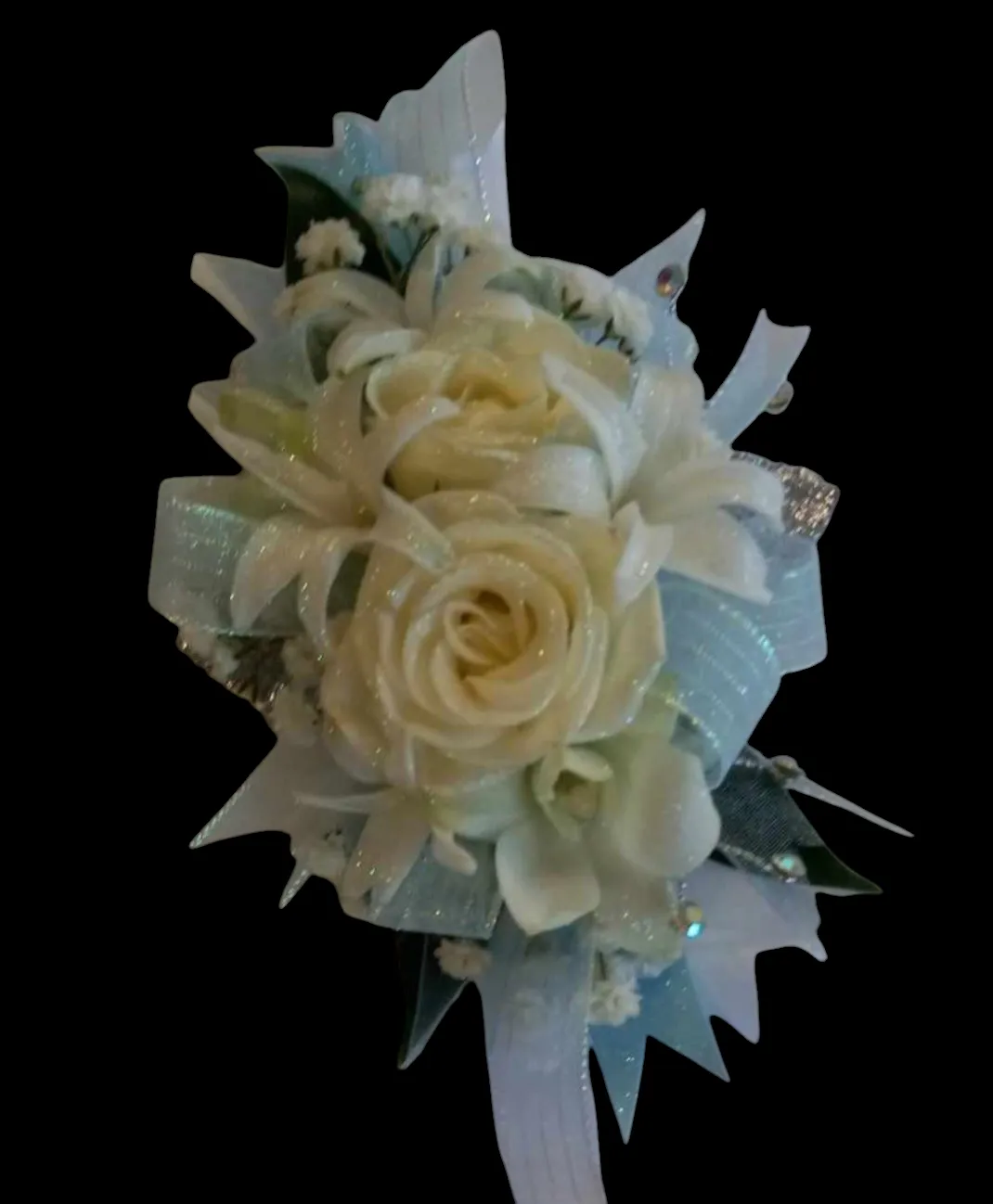 Floral wrist corsage with white rose, lilies, light blue ribbon, and glitter accents.