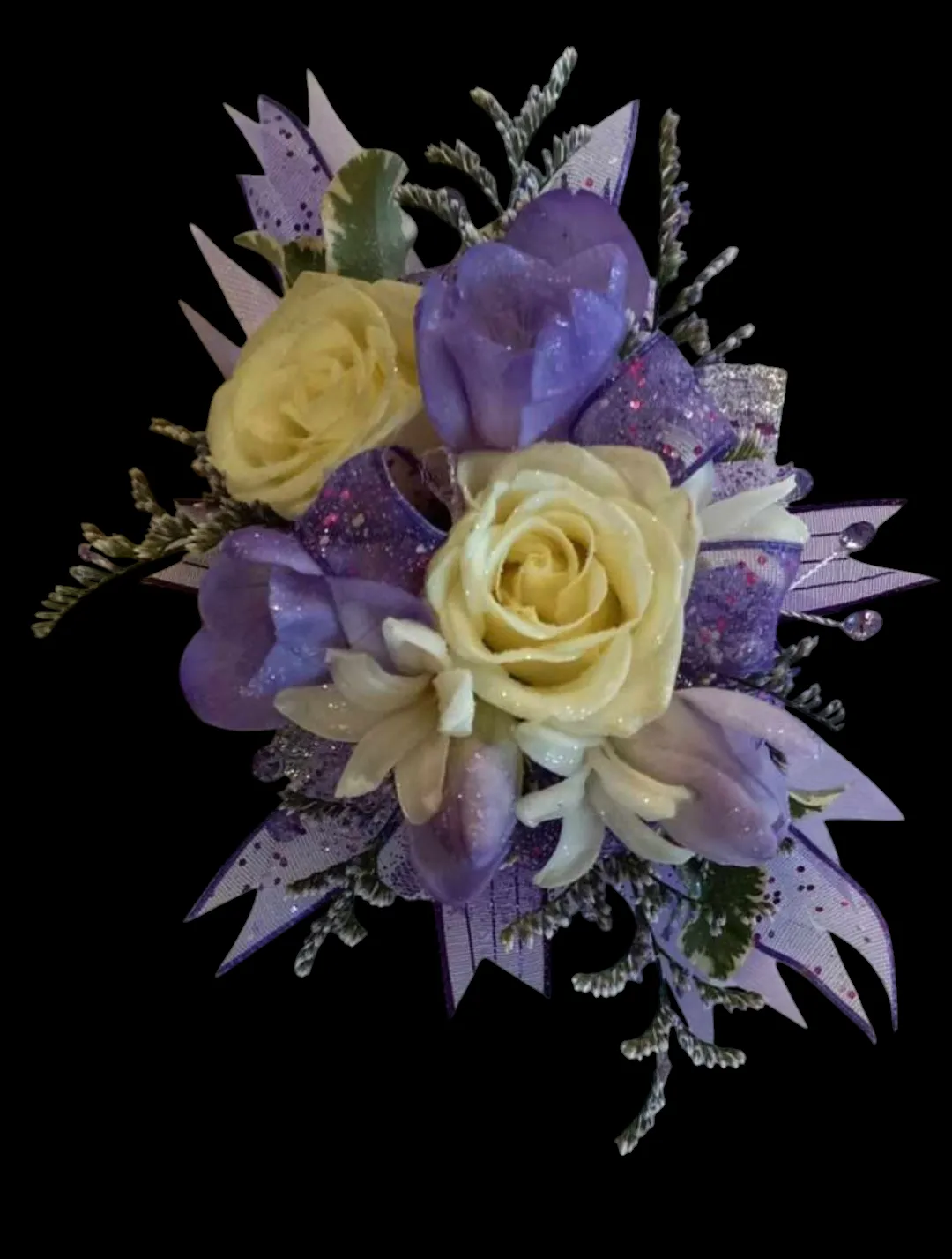 Purple and cream flower corsage with glitter ribbon against a black background.