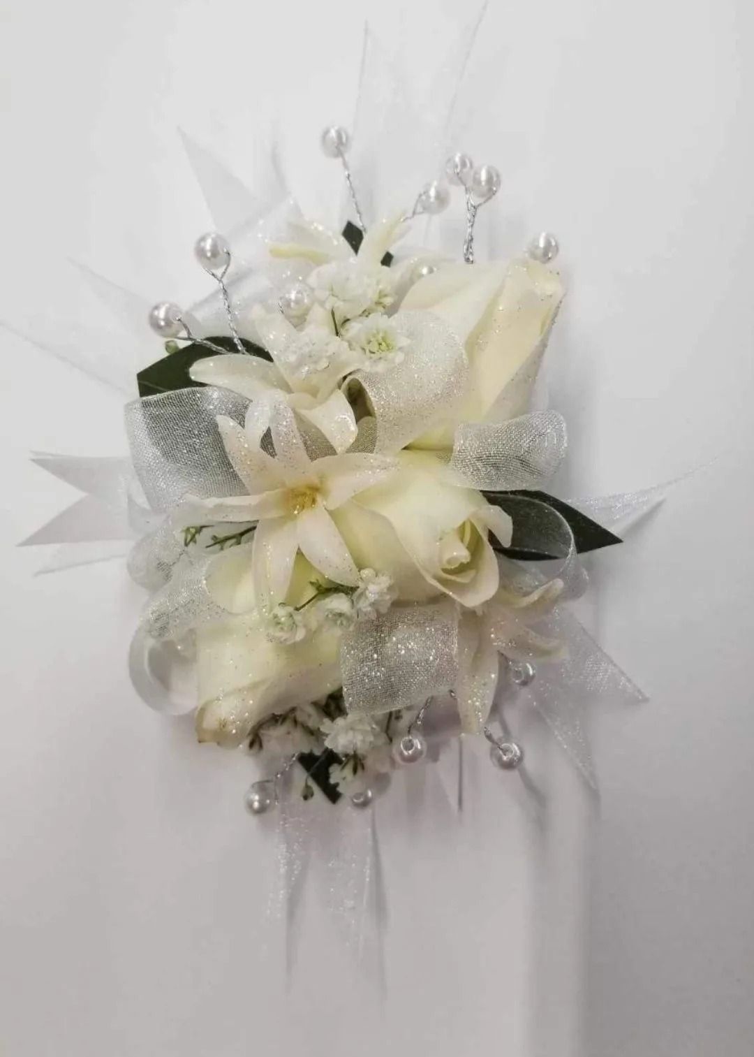 White floral wrist corsage with roses and pearls.