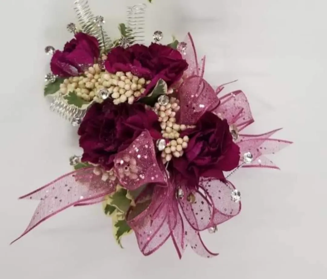 Burgundy floral wrist corsage with ribbon and embellishments.
