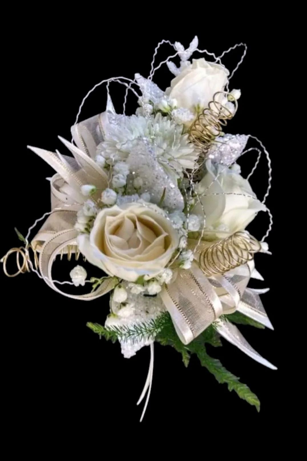 White and gold floral corsage with ribbon and accents on black background.